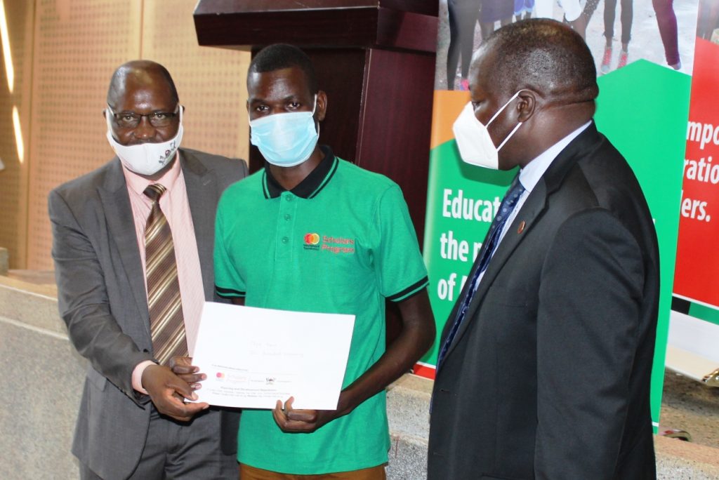 MCFSP Selection Committee Chairperson-Dr. Muhammad Ntale (L) and Principal CoCIS-Prof. Tonny Oyana (R) pose with a male beneficiary at the Award Ceremony.